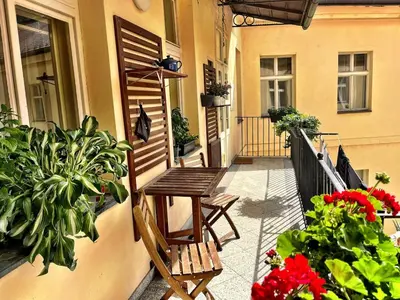 a balcony with a wooden table and chairs and flowers at Charming Old Town Retreat in Prague