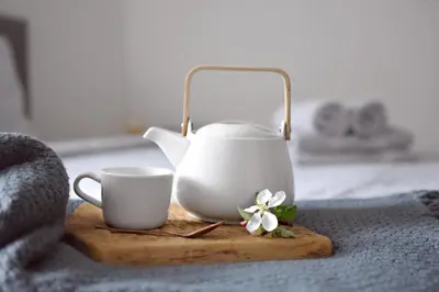 a tea kettle and a cup on a cutting board at Apartmány Ve stodole in Roudnice nad Labem