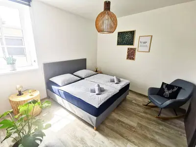 a small bedroom with a bed and a chair at Apartmány Ve stodole in Roudnice nad Labem