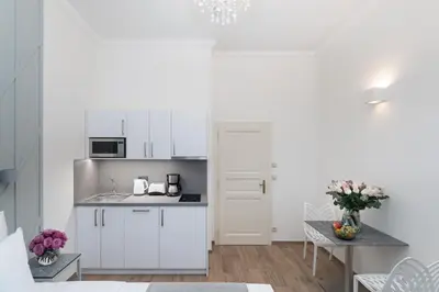 a kitchen with white cabinets and a table with flowers at Eight Secrets Boutique Residence by Dwellfort in Prague