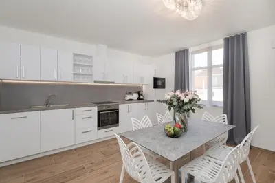 a kitchen with white cabinets and a table with flowers on it at Eight Secrets Boutique Residence by Dwellfort in Prague