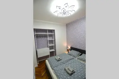 a bedroom with a bed and a chandelier at BRANDLY NEW APARTMENT ANDĚL in Prague