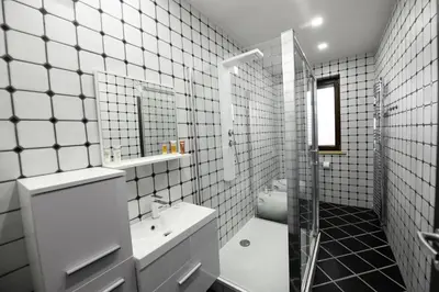 a white tiled bathroom with a sink and a shower at Atrium-Accomm in Řitka