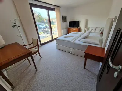 a bedroom with a bed and a table and a desk at Atrium-Accomm in Řitka