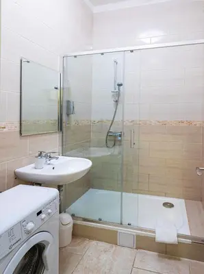 a bathroom with a shower and a sink and a washing machine at Michalska Apartment in Prague