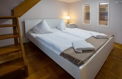 a large white bed with two pillows and a ladder at Michalska Apartment in Prague