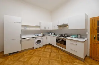 a kitchen with white appliances and a wooden floor at Apartment Manesova 4 in Prague