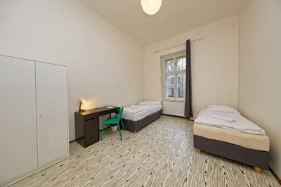 a room with two beds and a desk and a window at Apartment Manesova 4 in Prague