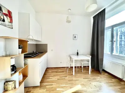 a kitchen with white cabinets and a white table at Maison Residence Prague in Prague