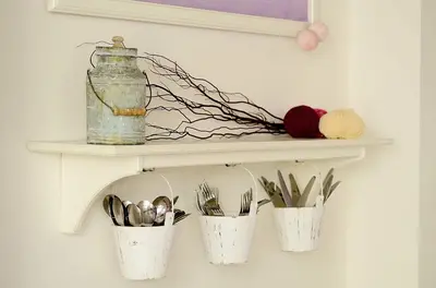a shelf with three white buckets with yarn and scissors at LaNoblessa in Prague
