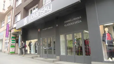 a woman is standing in front of a store at HU in Prague