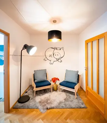 two chairs and a lamp in a room with a pig on the wall at Klimentska Cartoon apartments in Prague