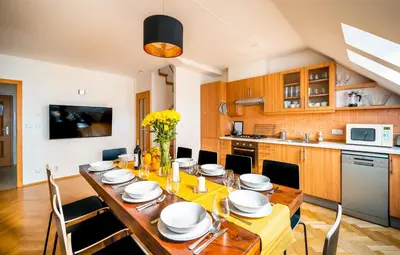 a dining room with a table and chairs and a kitchen at Klimentska Cartoon apartments in Prague