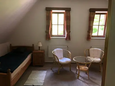 a bedroom with a bed and two chairs and a table at Malá Svatá Hora - penzion & restaurace in Mníšek pod Brdy