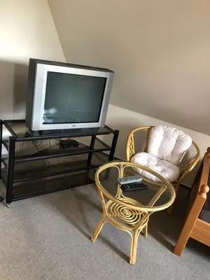 a living room with a tv and a chair and a table at Malá Svatá Hora - penzion & restaurace in Mníšek pod Brdy