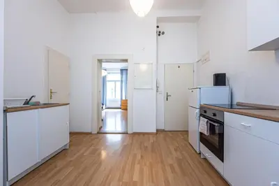 a kitchen with white cabinets and a wooden floor at Dittrichova Apartment in Prague