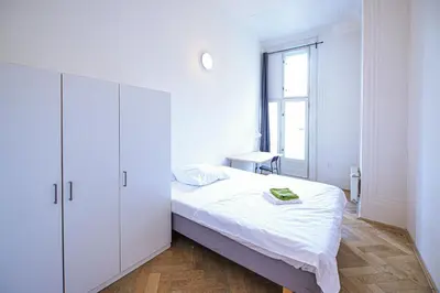 a white bedroom with a bed and a desk at Dittrichova Apartment in Prague