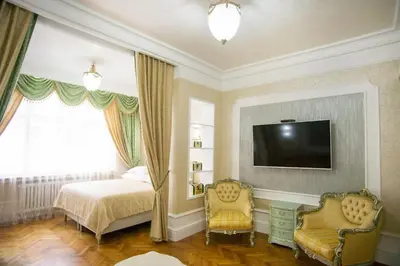 a bedroom with a bed and a tv and two chairs at Art Apartments Celakovskeho Sady in Prague