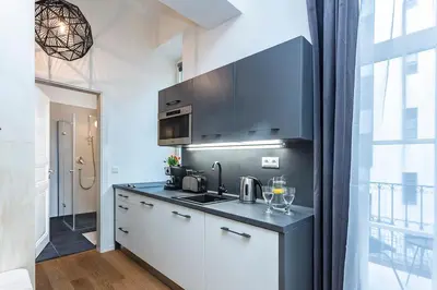 a kitchen with white cabinets and a black counter top at A Prague Apartments - Lesser Town in Prague