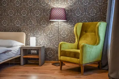 a bedroom with a green chair and a side table at Prague Locals Monastery Apartments in Prague