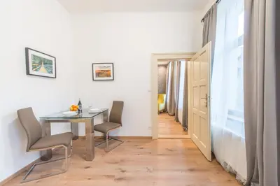 a dining room with a table and chairs and a hallway at Prague Locals Monastery Apartments in Prague