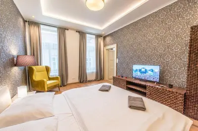 a bedroom with a bed and a tv and a chair at Prague Locals Monastery Apartments in Prague