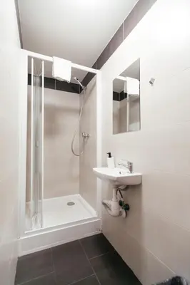 a white bathroom with a sink and a shower at Hostel Mandarinka in Prague
