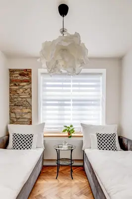 two beds in a room with a window and a chandelier at Design Pension Twenty 20 in Poděbrady