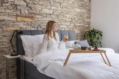 a woman sitting on a bed with a glass of wine at Design Pension Twenty 20 in Poděbrady