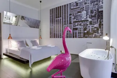 a pink flamingo in a bedroom with a bed and a tub at BRIGHT Prague Havelská in Prague