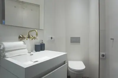 a white bathroom with a sink and a toilet at BRIGHT Prague Havelská in Prague