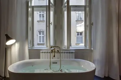a bath tub in a bathroom with two windows at BRIGHT Prague Havelská in Prague