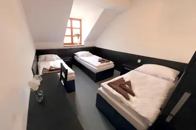 a room with two beds and a table and a window at Štiřínská stodola u Prahy in Kamenice