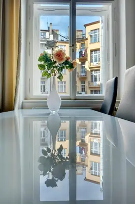 a vase with a flower on a table in front of a window at Kaprova - Old Town Apartments in Prague