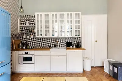 a kitchen with white cabinets and a black and white wall at Cubistic Residence Eliska / Jewish Quarter / Old Town in Prague