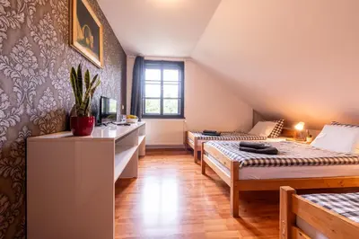 a room with two beds and a desk with a tv at Penzion Stříbrná Lhota in Mníšek pod Brdy