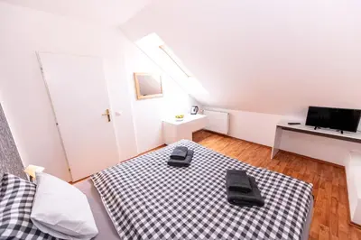 a small white room with a bed and a desk at Penzion Stříbrná Lhota in Mníšek pod Brdy