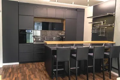 a kitchen with black cabinets and a bar with stools at Krejcarek Garden Apartment in Prague