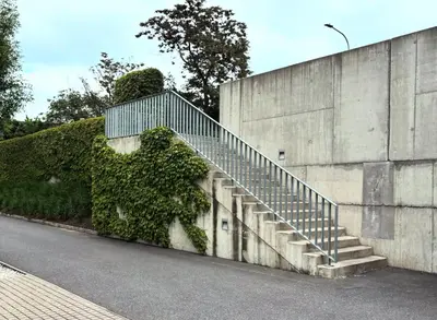 a staircase next to a concrete wall with ivy at Krejcarek Garden Apartment in Prague