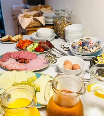a table with plates of food and glasses of juice at Penzion Laterna in Litoměřice
