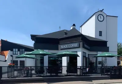 a cafe with tables and umbrellas in front of a building at Pension 1310 in Mladá Boleslav