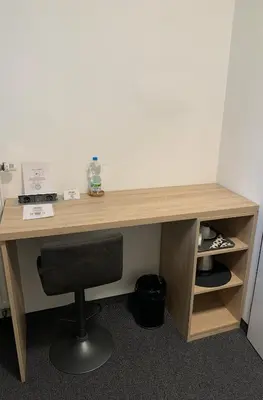 a wooden desk with a chair and a bottle of water at Pension 1310 in Mladá Boleslav