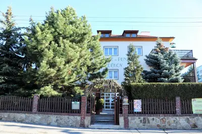 a building with a gate and trees in front of it at Penzion Bezděkov in Rakovník