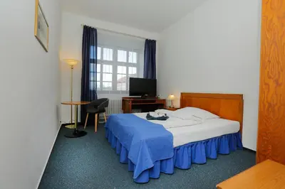 a bedroom with a bed and a desk and a television at Hotel Magnolia in Roudnice nad Labem