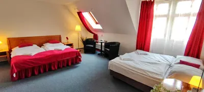 a hotel room with two beds with red curtains at Hotel Magnolia in Roudnice nad Labem