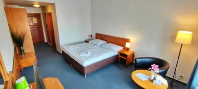 a bedroom with a bed and a table and a chair at Hotel Magnolia in Roudnice nad Labem