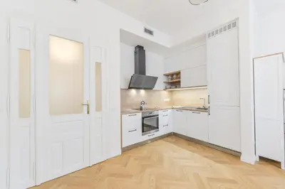 a white kitchen with white cabinets and a wooden floor at Brand New Apartment next to Old Town Square in Prague