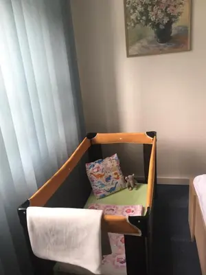 a crib with a pillow and a chair in a room at Blue apartment in beautiful English style garden with atmosphere in Prague