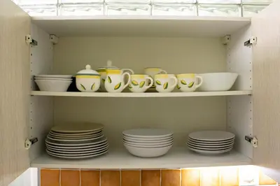 a cabinet filled with plates and cups and bowls at Blue apartment in beautiful English style garden with atmosphere in Prague