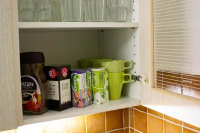 a kitchen pantry with cups and other items on a shelf at Blue apartment in beautiful English style garden with atmosphere in Prague